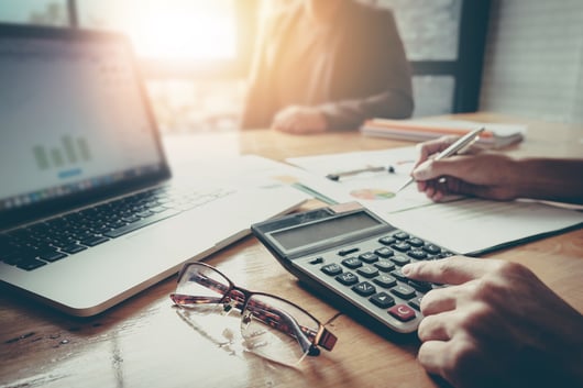 Businesspeople at conference table using laptop and calculator