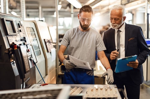 Manual worker and mature engineer checking quality of manufactured components