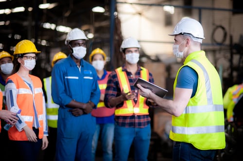 Manufacturers gathered on plant floor with masks on