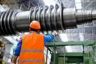 Man wearing hard hat and safety vest in manufacturing facility