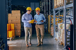 Two men walking and talking on manufacturing floor - 250x167